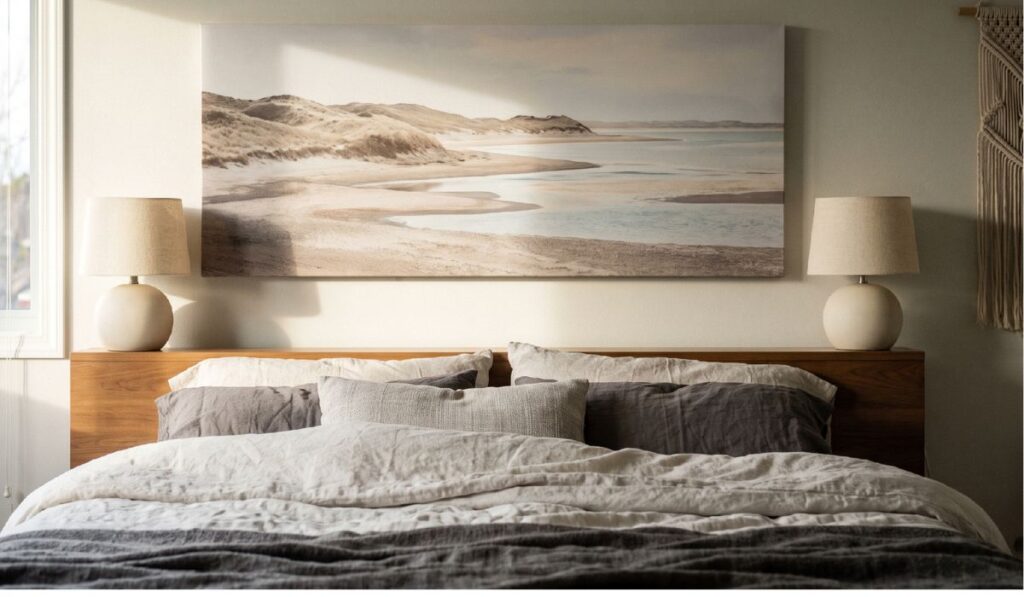 Positioned at eye level above the headboard, a panoramic landscape print sets a calm bedroom mood image